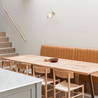 open plan kitchen diner with leather banquette seating and a kitchen island, skylight and wall lights