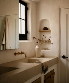 A modern organic bathroom with plaster walls an a wall niche for shelving