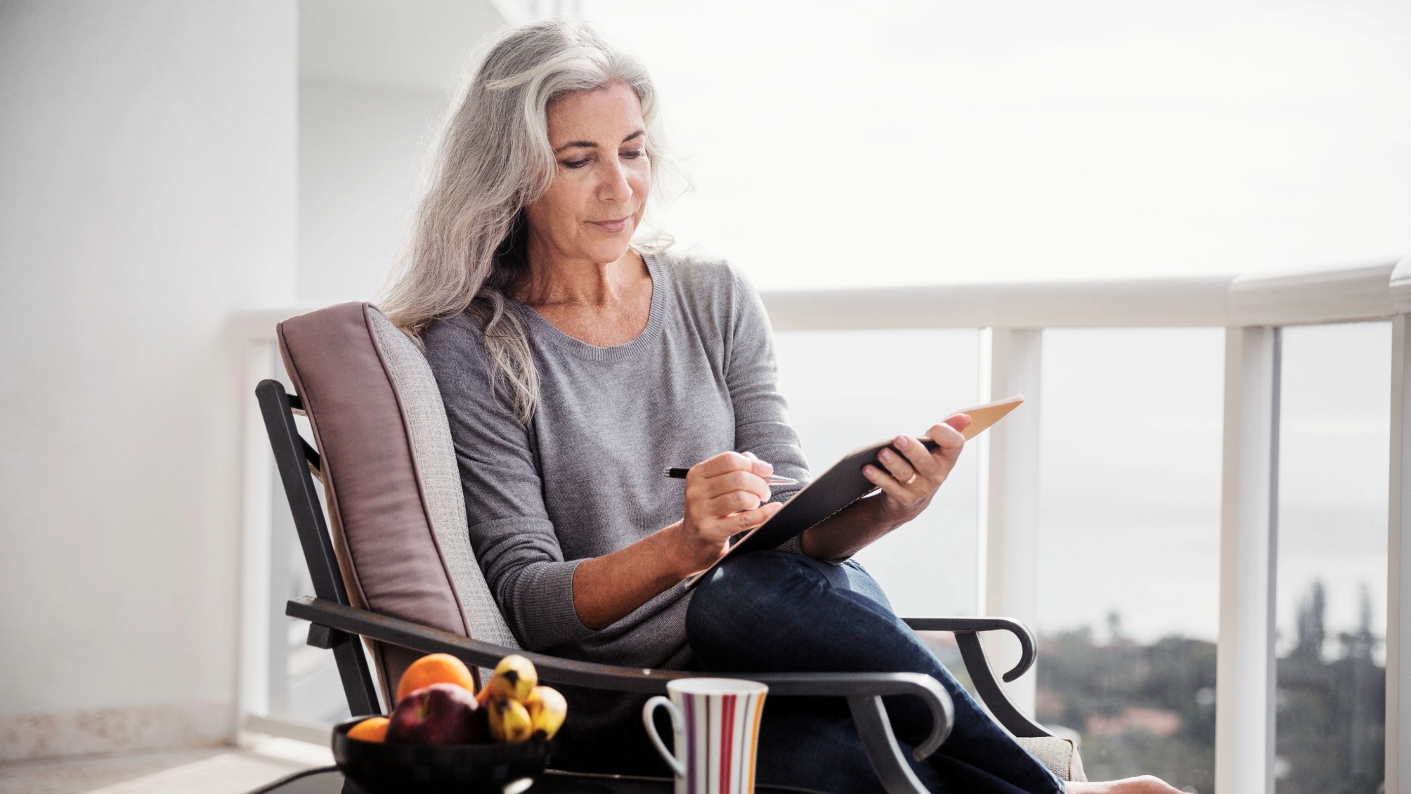 Mature woman sitting on chair on balcony 