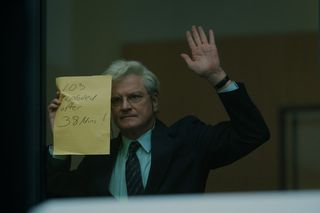 colin firth holds up a piece of paper to a window in a still from lockerbie