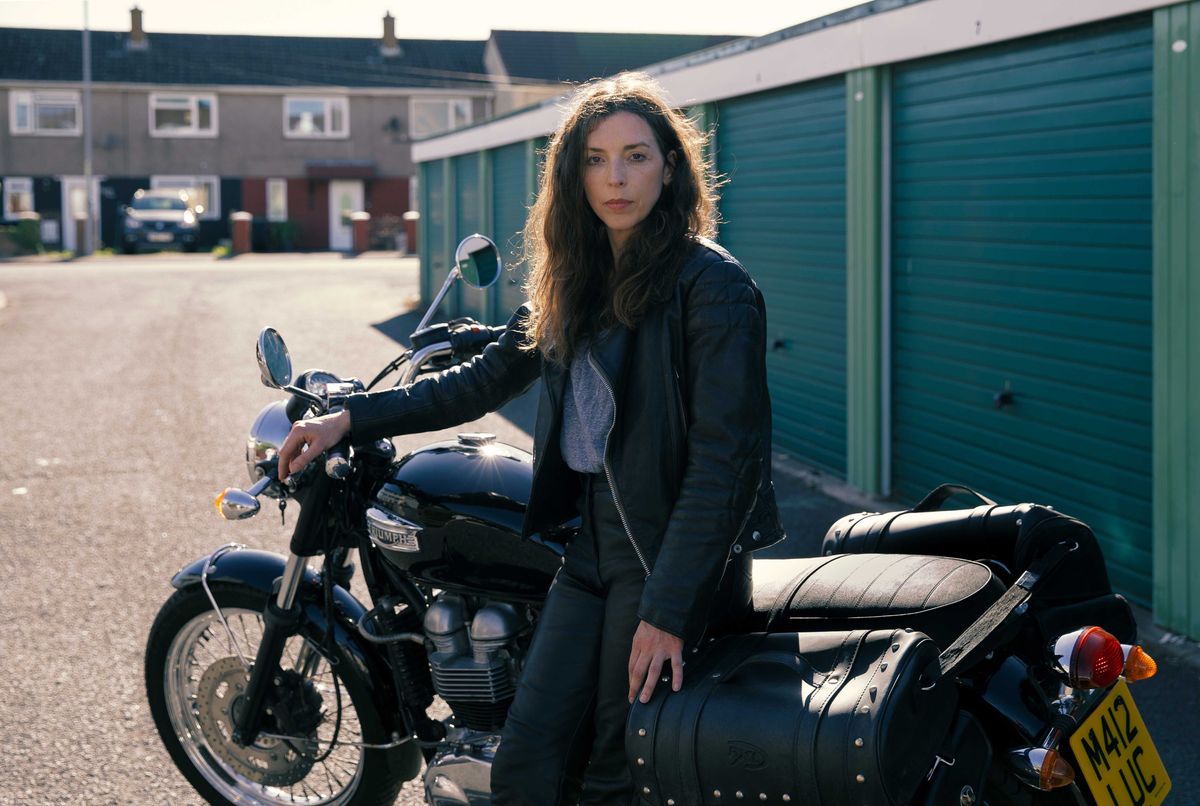 Bridget Christie as Linda posing by her Triumph motorbike in The Change.