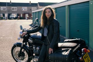 Bridget Christie as Linda posing by her Triumph motorbike in The Change.