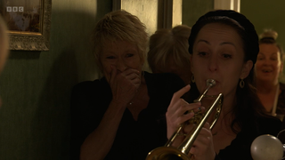 Sonia Fowler playing the trumpet as Shirley Carter laughs behind her