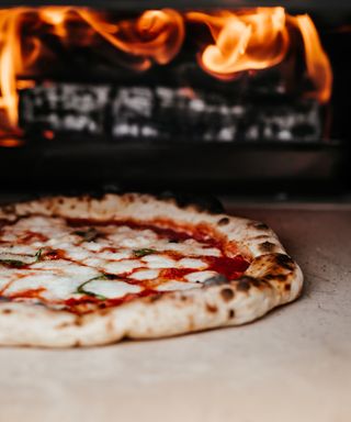 A pizza cooking inside an oven on a hot stone