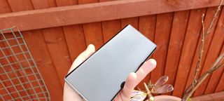 A white-backed Infinix Zero Ultra being held in a hand outside in a garden