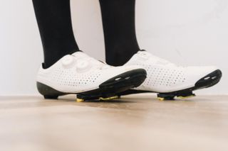 A close up of a white cycling shoe with a black socked foot in it