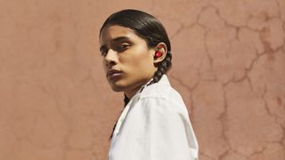 A girl with plaited hair wearing the Beats Studio Buds in red.