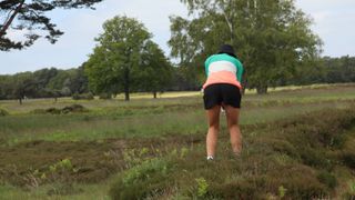 Female golfer playing from the rough