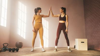 Progressive overload: Two women high fiving after a workout