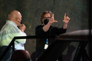 Director Davis Guggenheim is shown wearing a mask, making a frame with his thumbs and index fingers to look through, on the set of the documentary