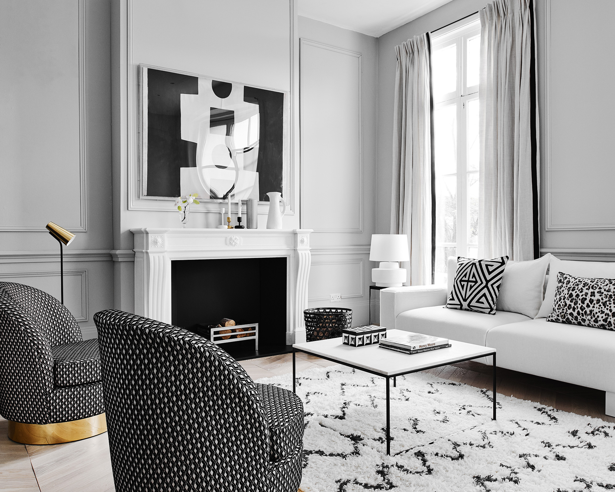 Pale grey living room ideas with black and white details in the furniture, rug and artwork.