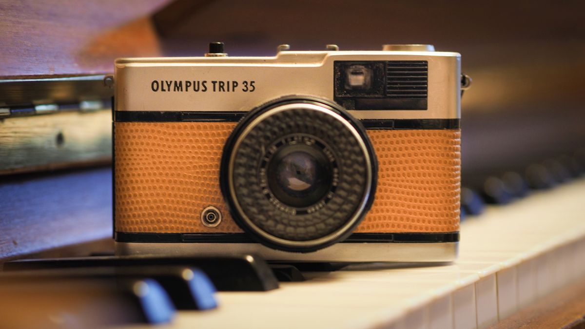 An Olympus Trip 35 sitting on the keys of a piano