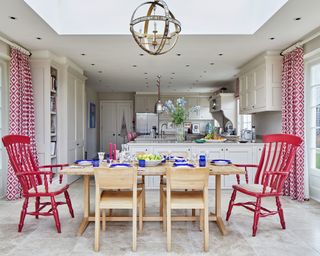 Neutral open plan kitchen ideas with a pop of red in the drapes and chairs.