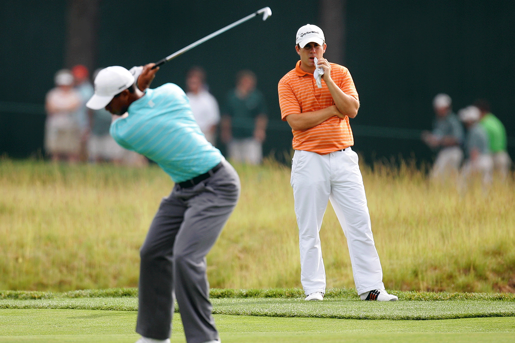 Tiger Woods hitting an iron shot from the fairway, with Richie Ramsay in the background watching Tiger play