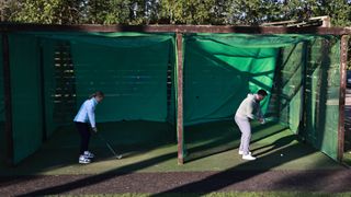 Two golfers hitting balls in the net