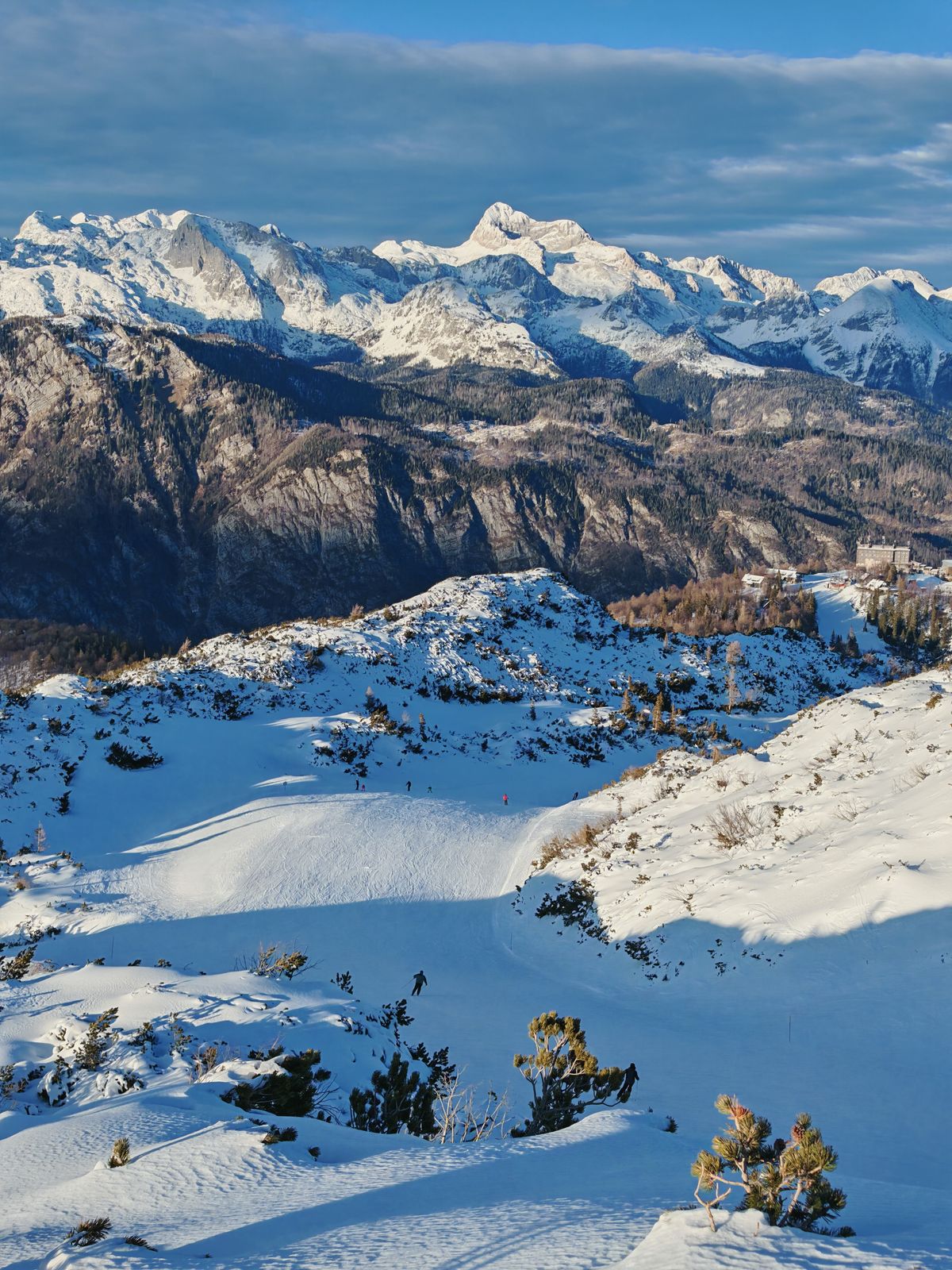 Ski trail in the sun in front of snowy mountains in the distance