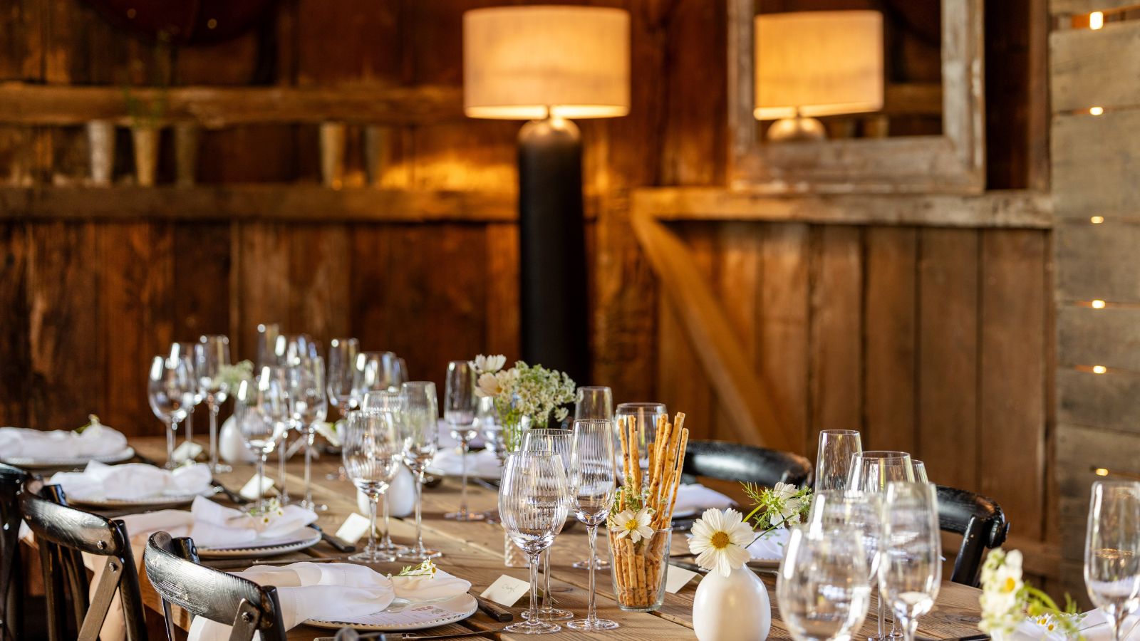 rustic table set up for dinner in a wooden barn