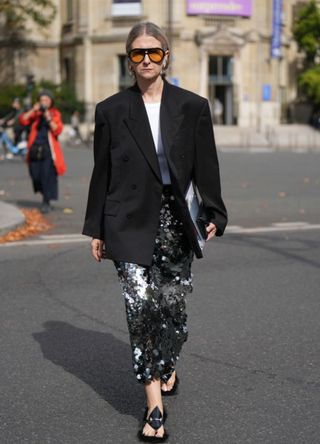 A woman wearing a long sequin skirt, tshirt and blazer