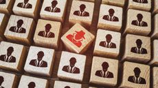 Red insider threat painted on Wooden cube surrounded by others with employee icons