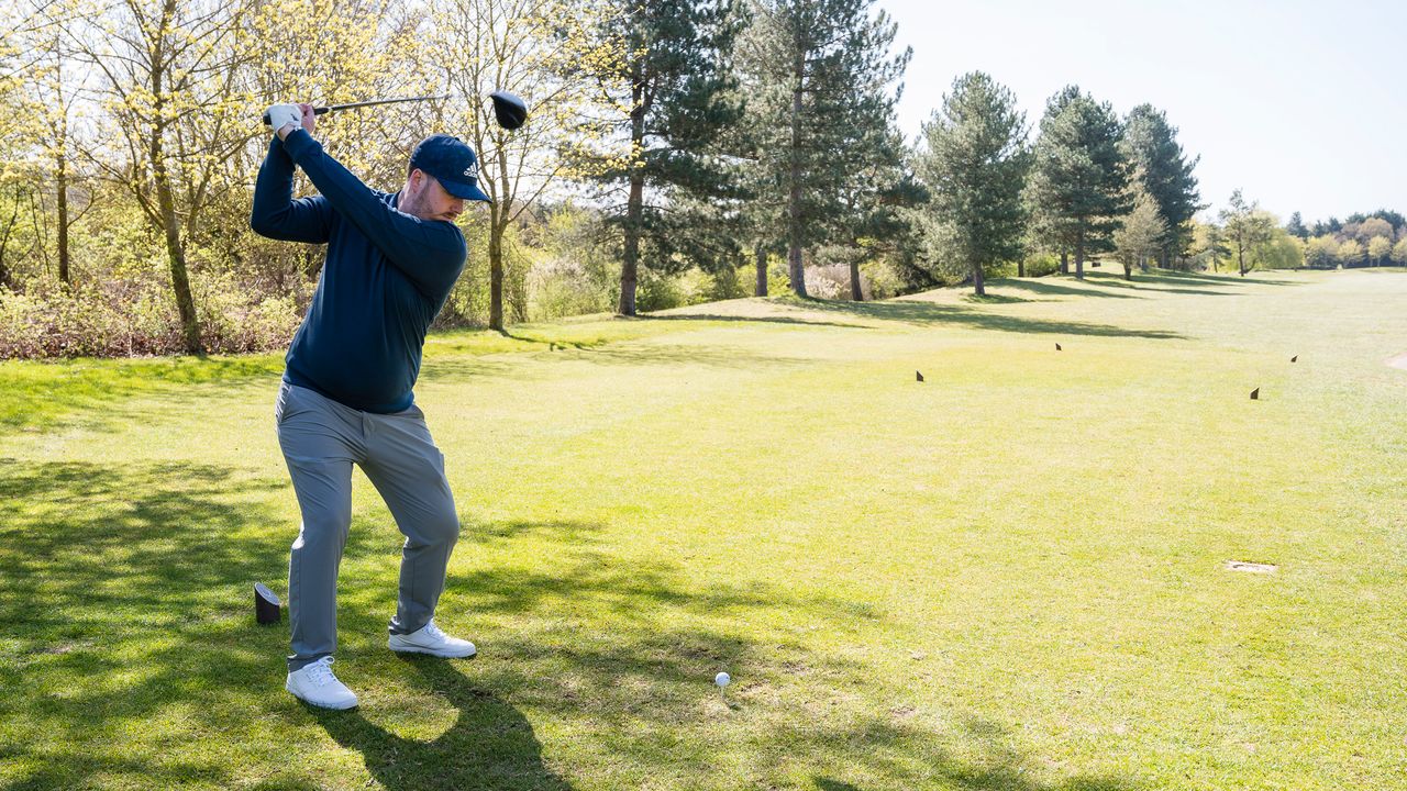 A golfer at the top of their backswing on a drive