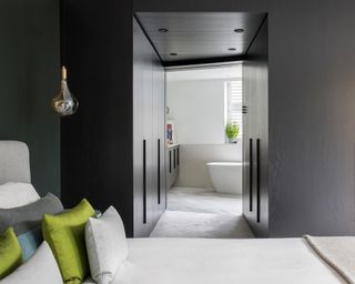 An example of ensuite ideas showing a view into a bright ensuite from a bedroom with dark walls