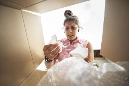 woman opens a box with a broken shipment