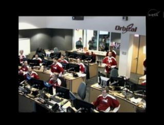 In Dulles, Va., Orbital Sciences Corp. flight controllers are seen clad in sporty mission shirts at the company's Cygnus spacecraft mission operations center during the Orb-1 cargo delivery mission's arrival at the International Space Station on Jan. 12,