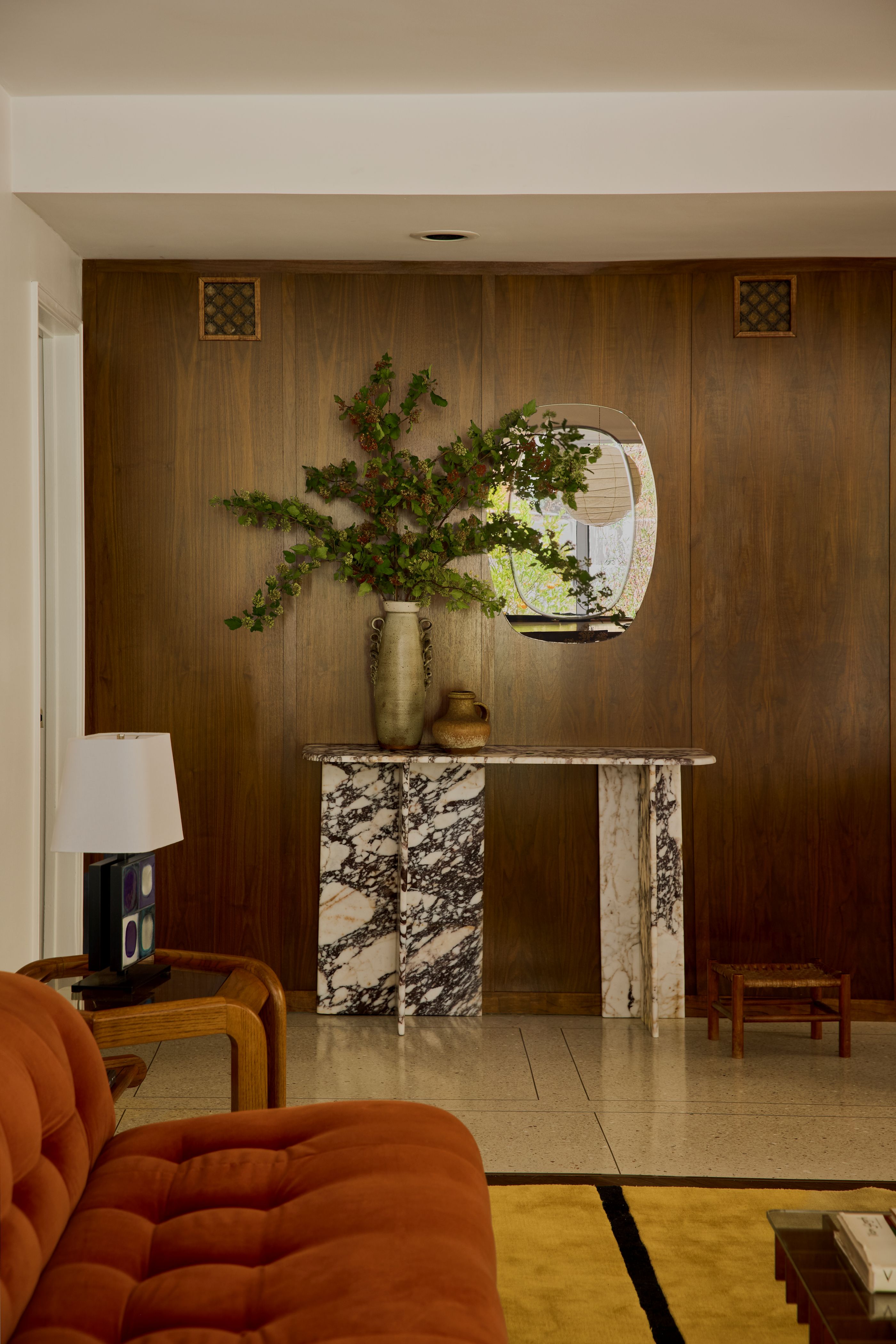 beautiful entryway with wooden walls and a marble console table with two vases