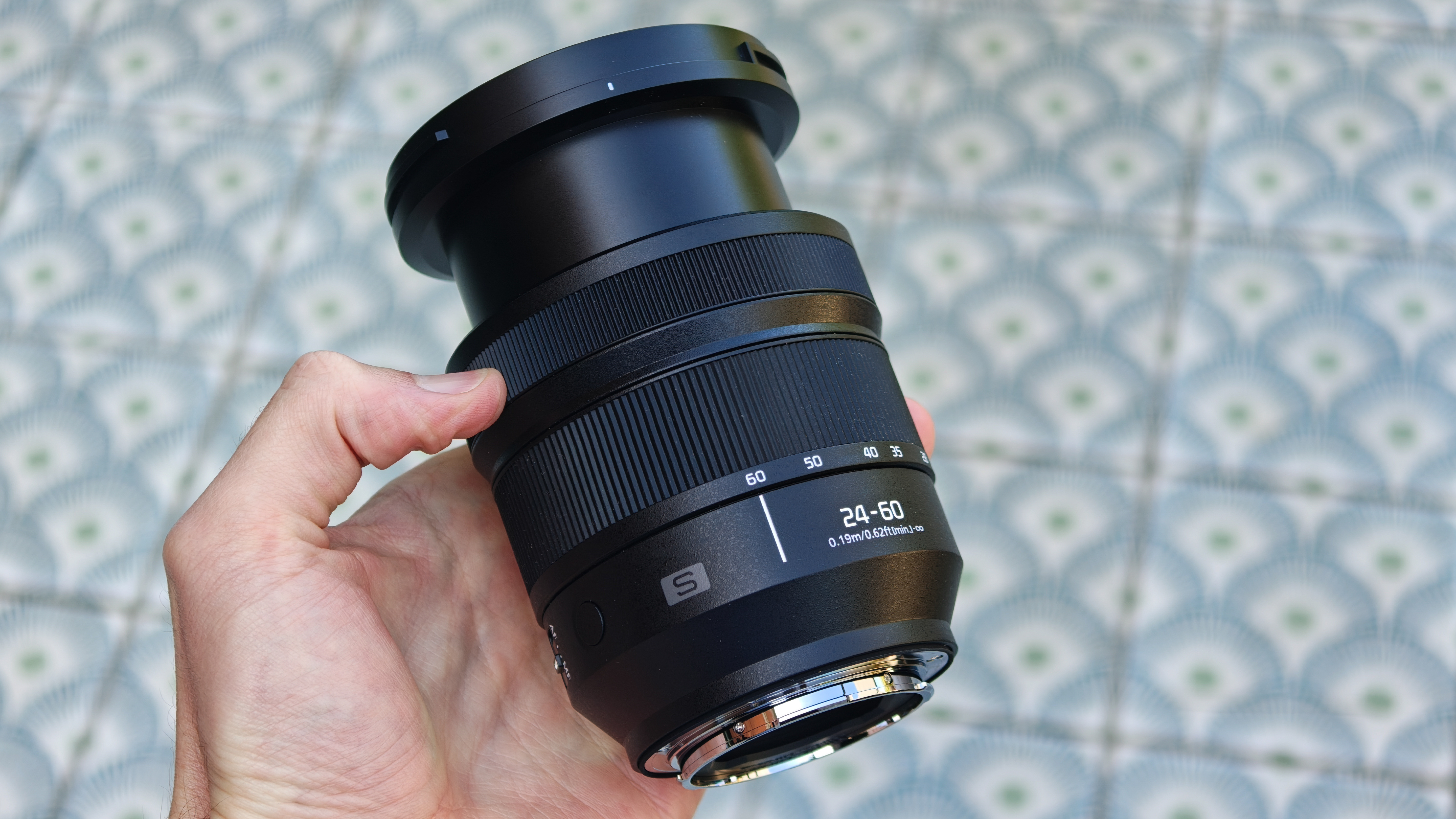 Panasonic Lumix S 24-60mm f/2.8 lens held in a hand
