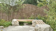 A show garden at Hampton Court with a wicker windbreak and wooden benches