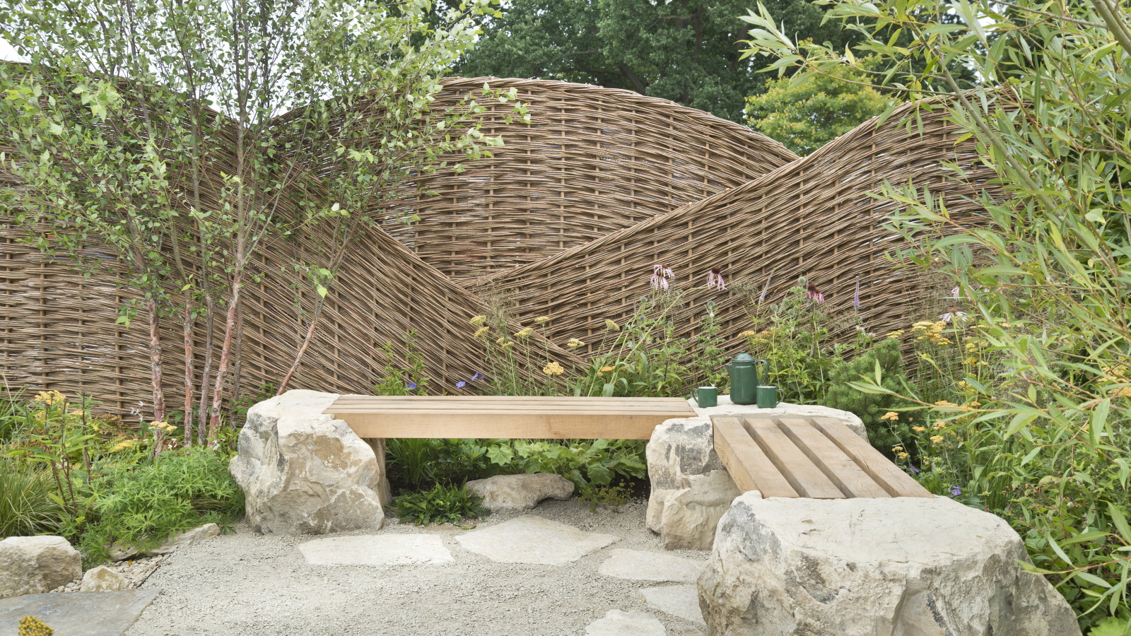 A show garden at Hampton Court with a wicker windbreak and wooden benches