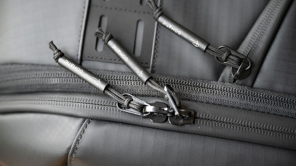 Closeup of the zips of the Gomatic McKinnon Camera Pack 35L on a wooden table