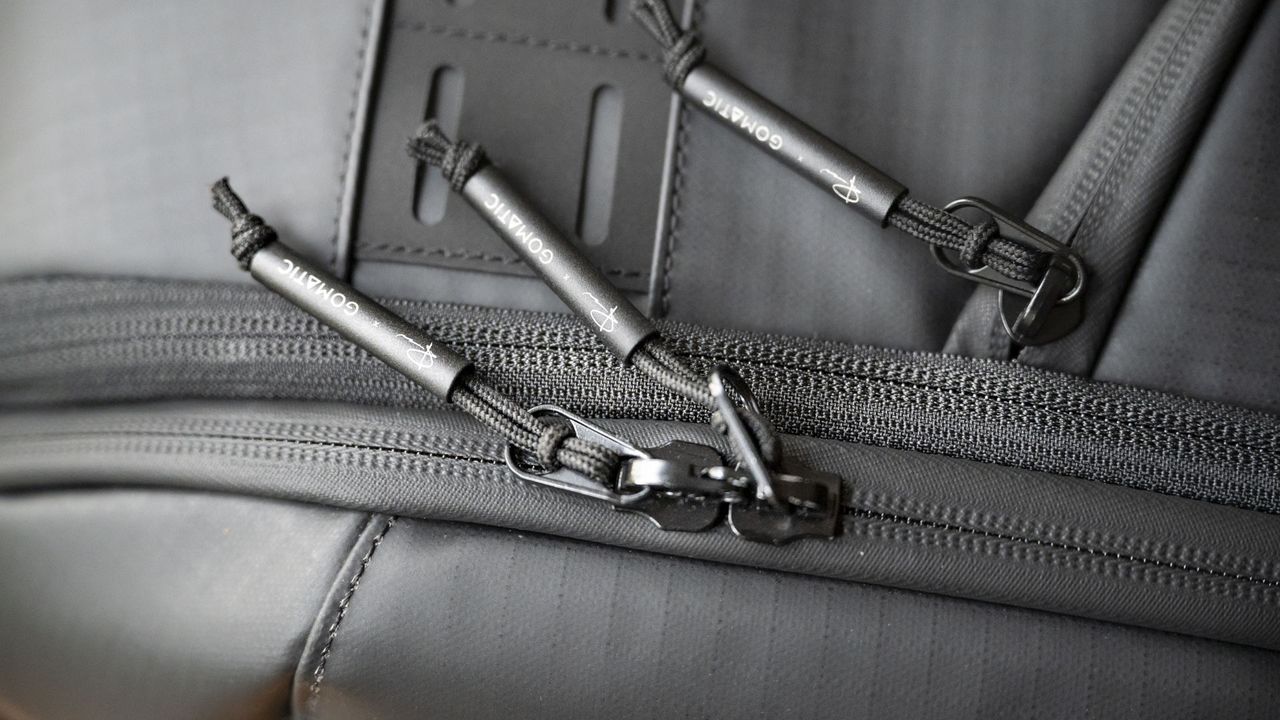 Closeup of the zips of the Gomatic McKinnon Camera Pack 35L on a wooden table