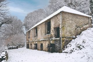 A derelict tumbledown barn covered by snow