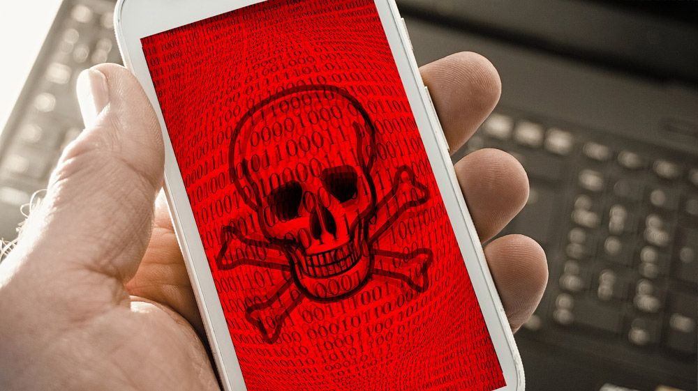 White smartphone displaying skull and crossbones on red screen background.