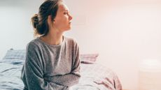 woman sat on her bed holding her stomach