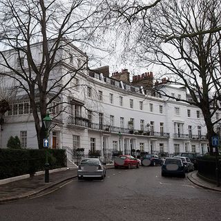 white coloured building with trees and cars