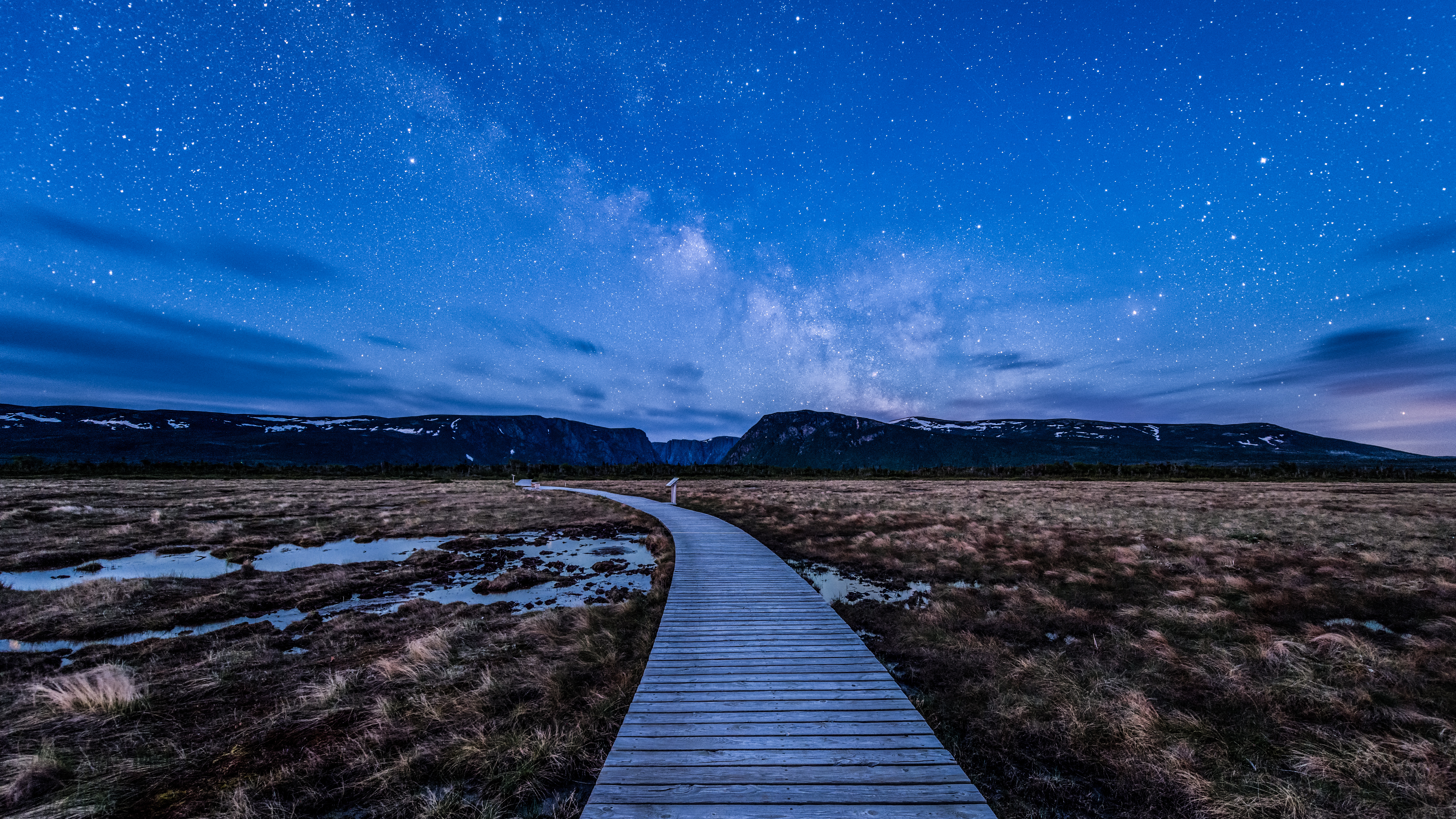 Milky Way at blue hour over boardwalk on hiking trail to Western Brook Pond in Gros Morne National Park, Canada