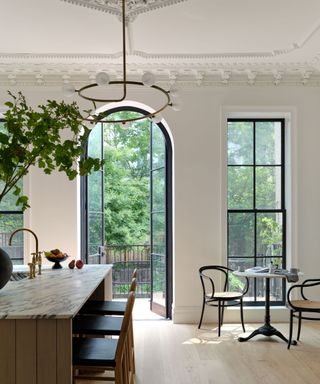 A black and white kitchen with a large black arched door looking outdoors