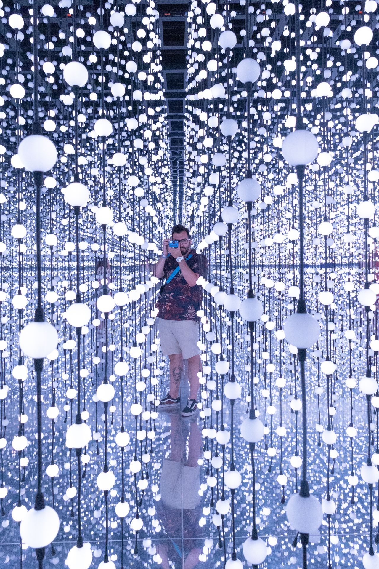 A photo of multiple lights and a man using an instant camera taken on a Canon EOS R50 V mirrorless video camera