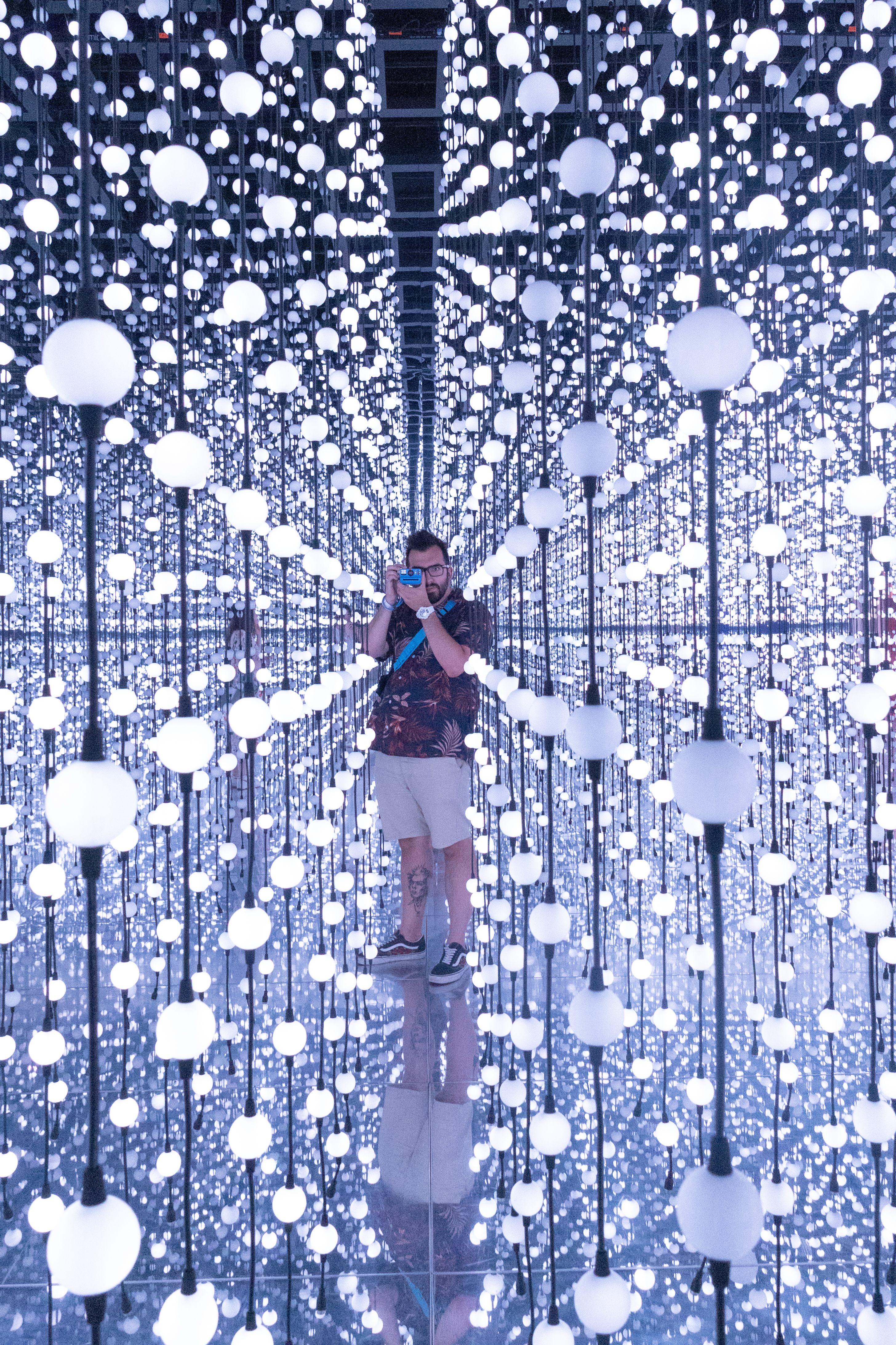 A photo of multiple lights and a man using an instant camera taken on a Canon EOS R50 V mirrorless video camera