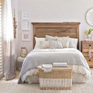 Fish-print wallpaper on feature wall, bedroom, wooden bedstead and matching chest of drawers, coastal motifs, neutral beige sisal carpet, wicker basket