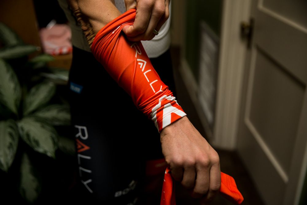 A rider pulls on a new Rally Cycling arm warmer.
