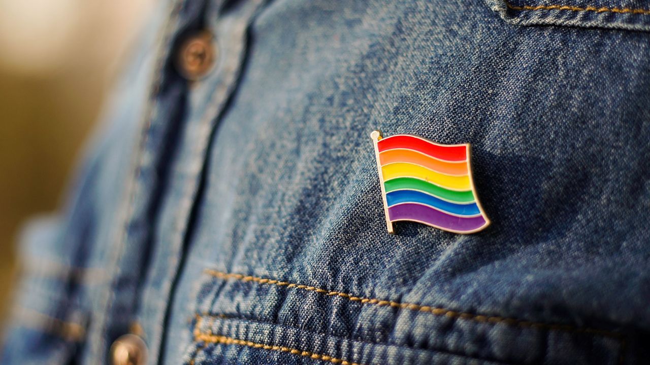 A small Pride flag pin on a person&#039;s denim shirt.