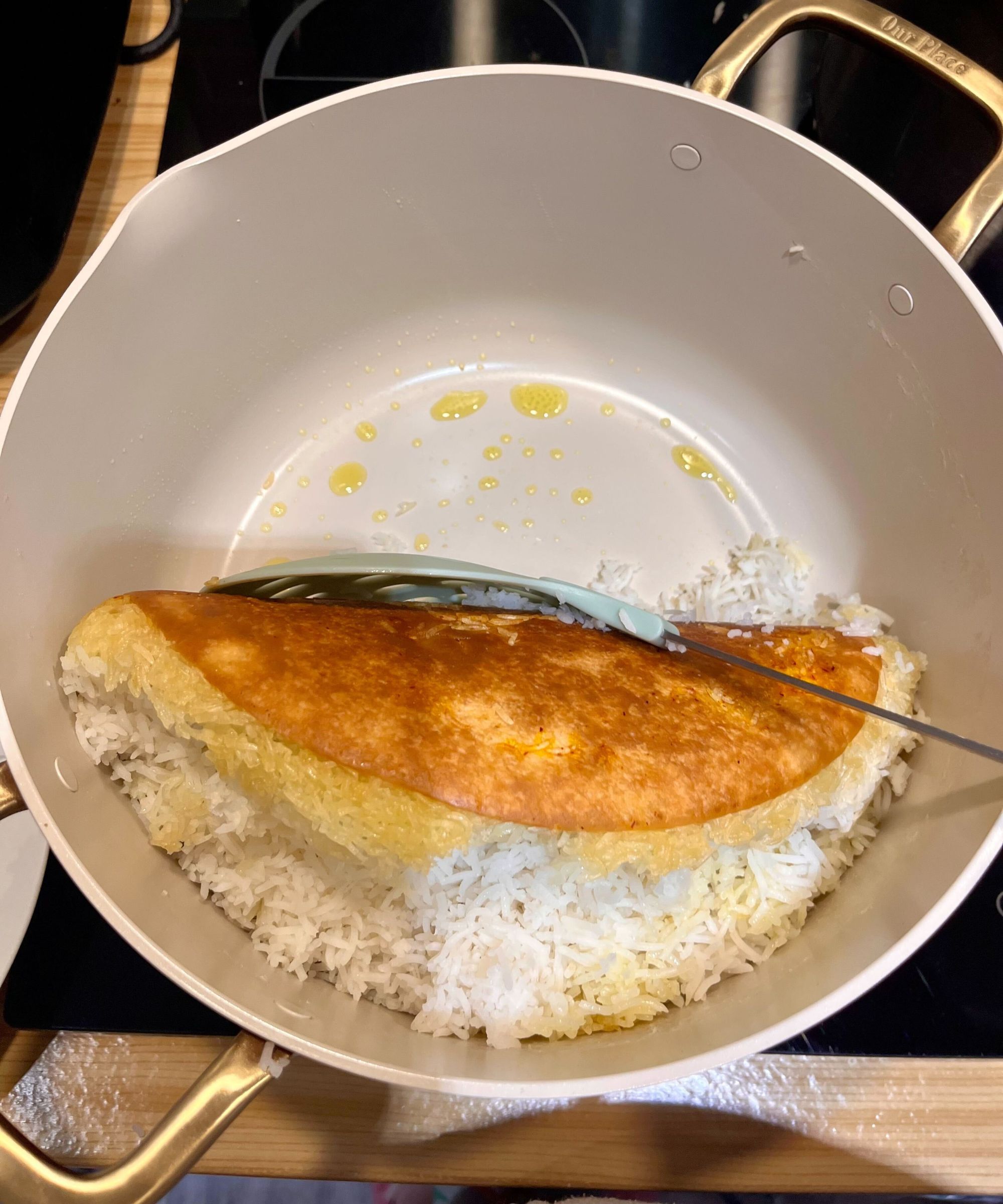 The tahdig was perfectly golden brown all over with no sticking or burning, seen here being lifted off the base of the stock pot in one piece using a large round slatted silicone utensil
