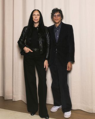 photography duo inez and vinoodh, wearing black pants and a sparkly black top and a black suit, pose together at an event