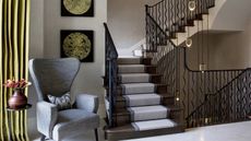 Staircase lighting ideas by Rebecca Hughes Interiors with suspended lights, green curtains, grey staircase runner and grey chair