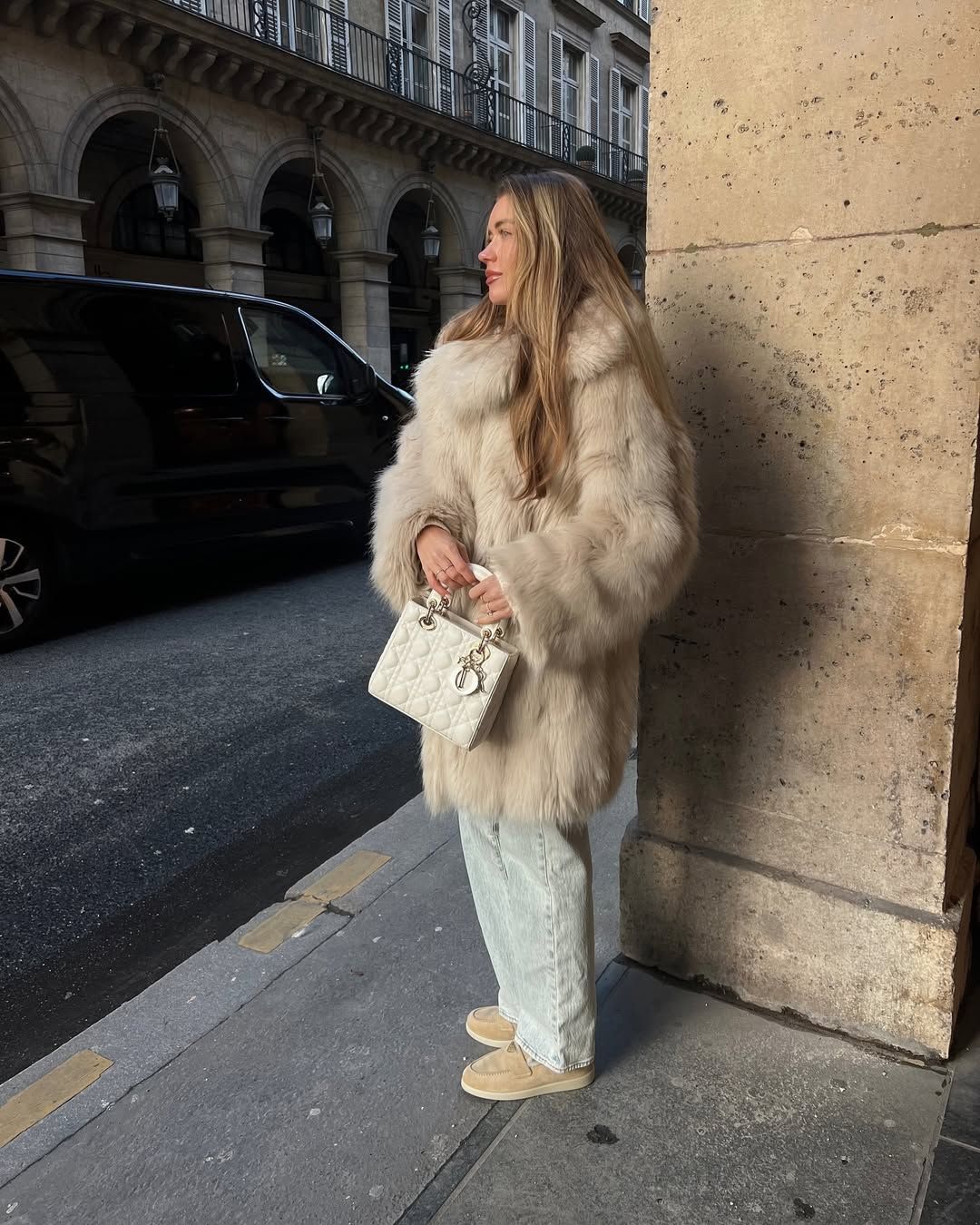 @lovisabarkman wears a pair of beige suede shearling loafers from Prada with light wash blue jeans, a fluffy faux fur coat and a white Lady Dior bag