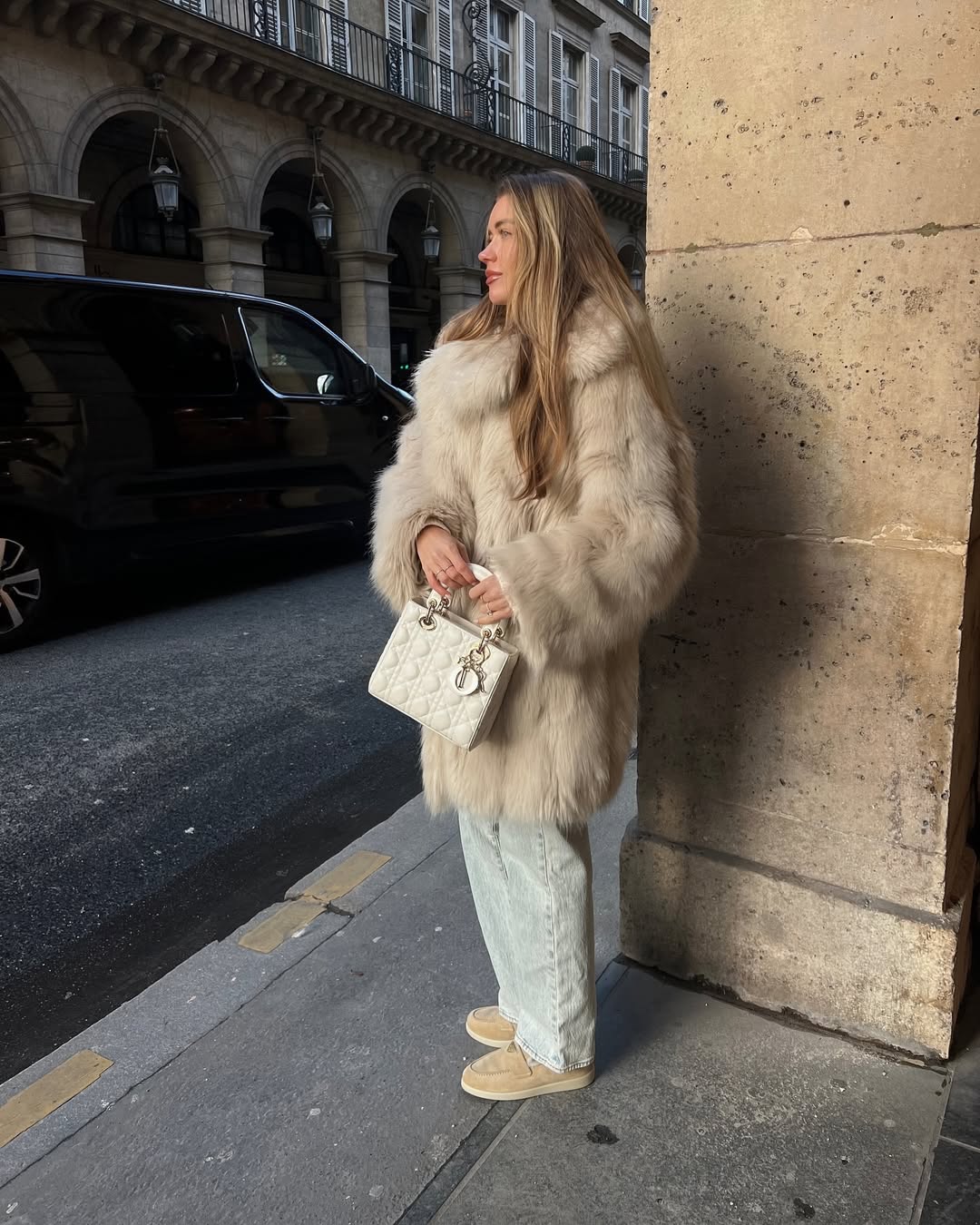 @lovisabarkman wears a pair of beige suede shearling loafers from Prada with light wash blue jeans, a fluffy faux fur coat and a white Lady Dior bag