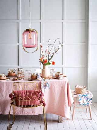 Pink dining table and accessories with soft grey wall paneling
